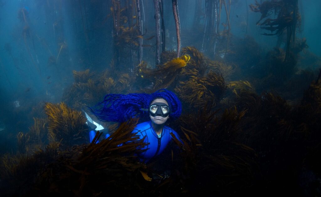 woman underwater surrounded by plants